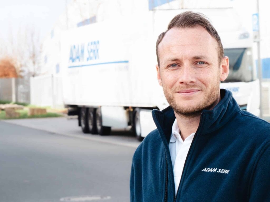 Fuhrparkleiter Dominik Schmitt vor einem E-LKW von Adam Serr